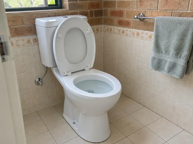 Clean white toilet in a tiled bathroom with beige walls and floor in Schofields